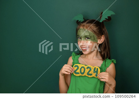 A laughing girl with made-up face in the shape of a dragon shows numbers of 2024 109500264