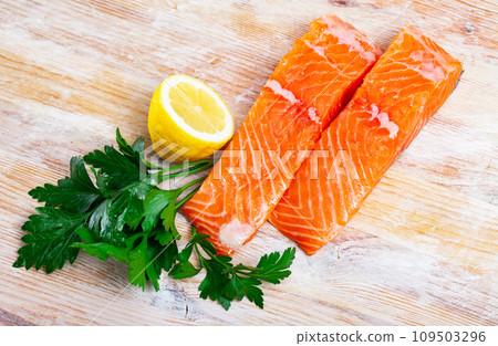 Raw salmon fillet with lemon and greens before cooking 109503296