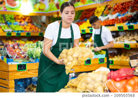 Young saleswoman lays out packaged potatoes for sale 109503568