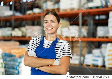 Positive warehouse girl employee stands with arms crossed over chest. Positive warehouse girl employee stands with arms crossed over chest. 109503571