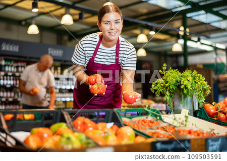 Smiling young saleswoman offering ripe tomatoes in eco products store 109503591