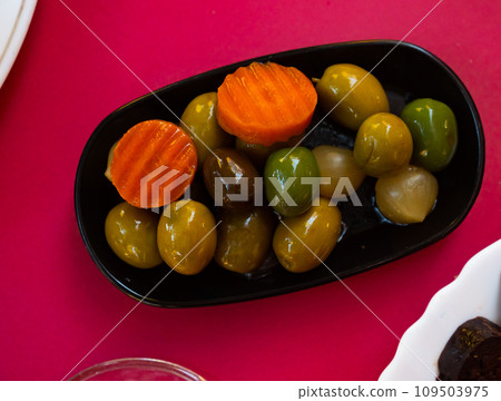 Bowl filled with green Spanish olives with onions, cucumbers and carrots 109503975