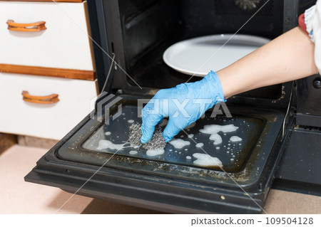 Male hands cleaning microwave oven with metal scrubber 109504128