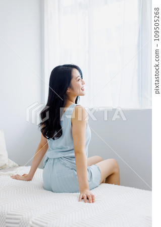 A woman standing by the window in the morning 109505268