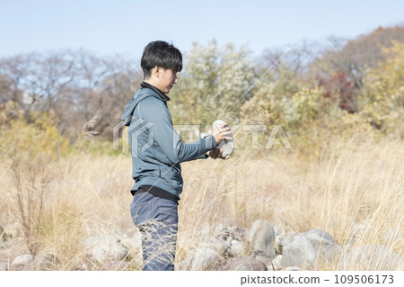 一名男子在河岸上尋找可用於平衡岩石的石頭。 一名男子在河岸上尋找可用於平衡岩石的石頭。 109506173