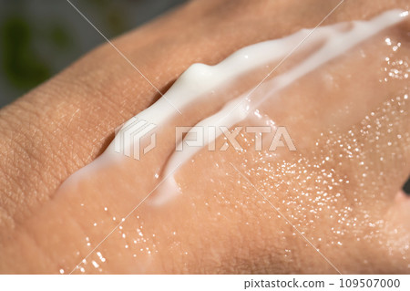 A smear of white moisturizer or sunscreen on a woman's hand. 109507000