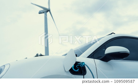 Electric car recharging energy from charging station in wind turbine farm.Peruse Electric car recharging energy from charging station in wind turbine farm.Peruse 109509587