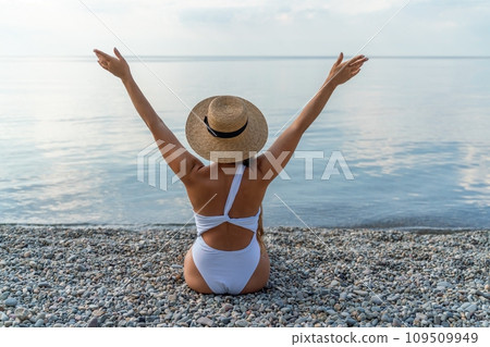 Woman white bikini beach tan. Happy woman in swimwear and hat on vacation. Summer travel holidays vacation on the sea 109509949
