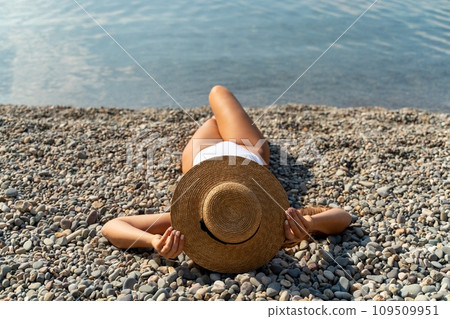 Woman white bikini beach tan. Happy woman in swimwear and hat on vacation. Summer travel holidays vacation on the sea 109509951