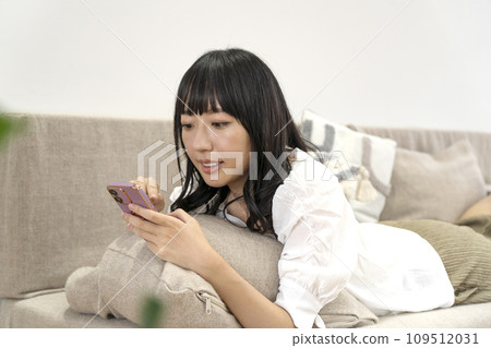一個女人在家放鬆並操作智慧型手機 一個女人在家放鬆並操作智慧型手機 109512031