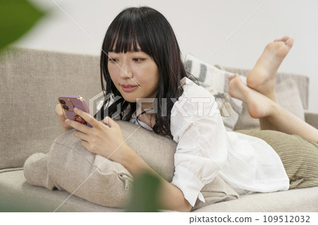 一個女人在家放鬆並操作智慧型手機 一個女人在家放鬆並操作智慧型手機 109512032