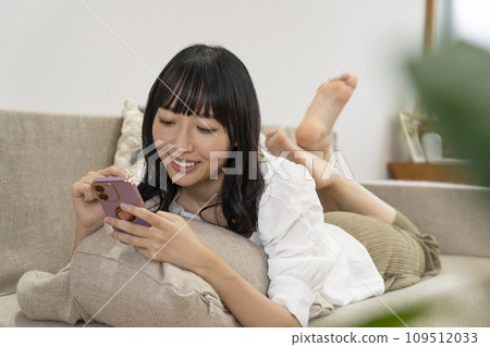 一個女人在家放鬆並操作智慧型手機 一個女人在家放鬆並操作智慧型手機 109512033
