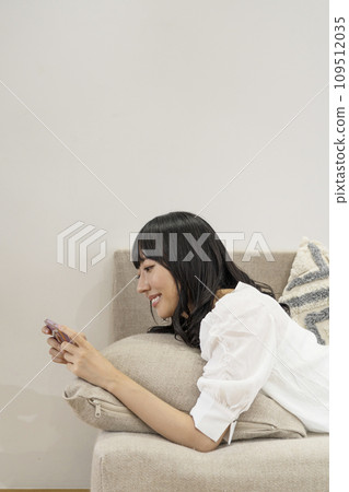 一個女人在家放鬆並操作智慧型手機 109512035