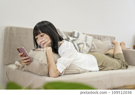 一個女人在家放鬆並操作智慧型手機 109512036