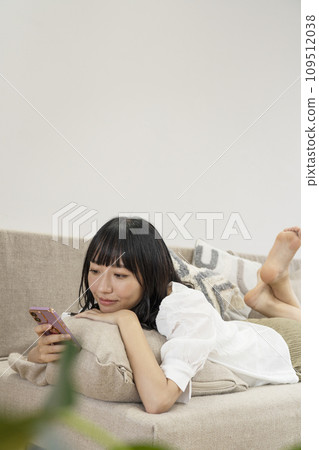 一個女人在家放鬆並操作智慧型手機 一個女人在家放鬆並操作智慧型手機 109512038
