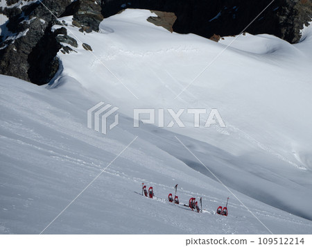 Saas Fee, Switzerland - June 16th 2023: Snow shoe depot on the steep glacier for the ascent to Strahlhorn peak Saas Fee, Switzerland - June 16th 2023: Snow shoe depot on the steep glacier for the ascent to Strahlhorn peak 109512214