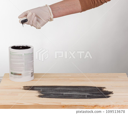 painting wooden background, hand with brush and can of paint 109513678