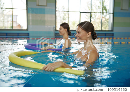Two young women training with noodles at swimming pool Two young women training with noodles at swimming pool 109514360