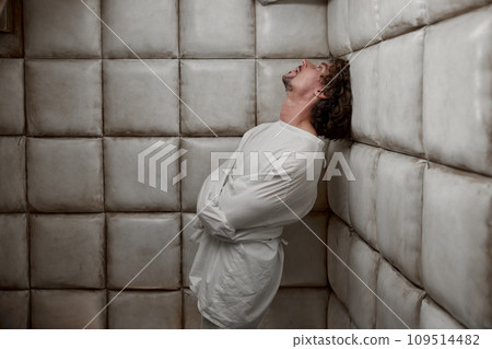 Calm man with schizophrenia mental disorder in white padded room 109514482