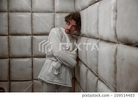 Calm man with schizophrenia mental disorder in white padded room 109514483