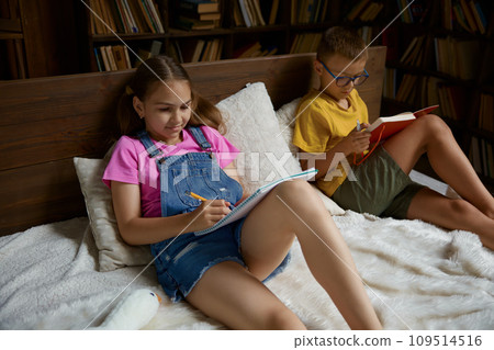 Little sister and brother doing homework lying in bed 109514516