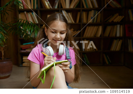 Closeup portrait of little smart schoolgirl writing in her diary Closeup portrait of little smart schoolgirl writing in her diary 109514519