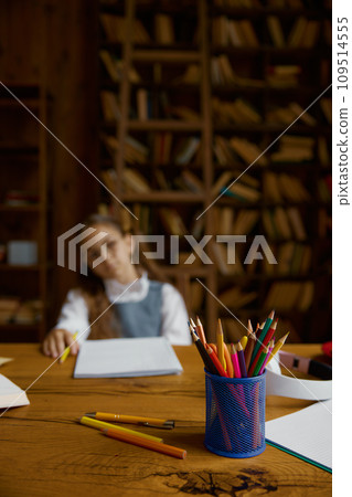 Tired schoolgirl studying at home, selective focus on stationery glass Tired schoolgirl studying at home, selective focus on stationery glass 109514555