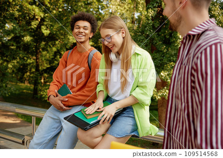 Confident smiling university students chatting together while taking rest Confident smiling university students chatting together while taking rest 109514568