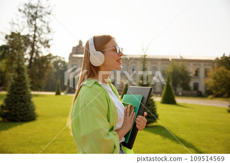 Side view portrait of satisfied female student wearing headphones Side view portrait of satisfied female student wearing headphones 109514569