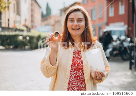 Happy woman holding Sicilian cannolo tube pastry filled with chocolate. Travel, Italy and holidays concept. Young women eating delicious cake cannoli, Traveling Europe in summer 109515660