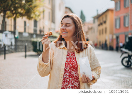 Happy woman holding Sicilian cannolo tube pastry filled with cream. Travel, Italy and holidays concept. Young women eating traditional delicious cake cannoli, Traveling Europe in summer 109515661