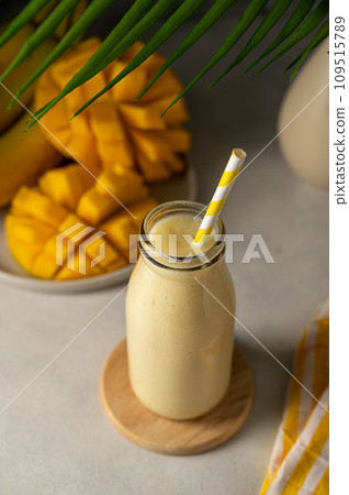 Bottle of mango, banana and yoghurt smoothie with a straw. Bottle of mango, banana and yoghurt smoothie with a straw. 109515789
