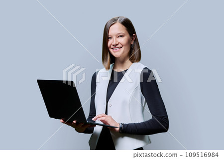 Portrait of young business woman using laptop on gray background 109516984