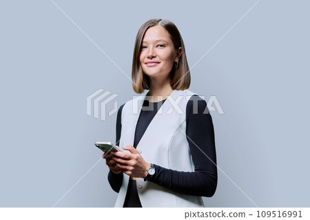 Young trendy woman using smartphone on gray background Young trendy woman using smartphone on gray background 109516991