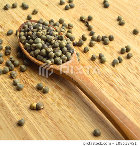 Dried okra seeds in wooden spoon, on bamboo cutting board 109518451