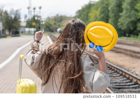 Free road: in bright clothes and with a suitcase, a woman is ready to go from word to deed and go on a trip. Shrouded in dreams: a woman with a suitcase in yellow clothes gives a feeling of future 109518531