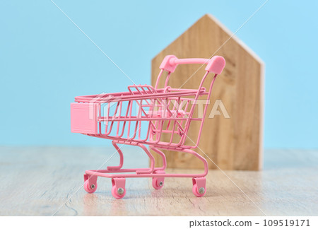 Wooden house and miniature shopping cart, representing the concept of real estate purchase, rental growth Wooden house and miniature shopping cart, representing the concept of real estate purchase, rental growth 109519171