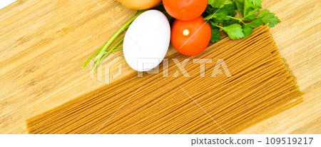 Raw healthy macaroni pasta stick and organic tomato, parsley, egg and onion, on bamboo cutting board Raw healthy macaroni pasta stick and organic tomato, parsley, egg and onion, on bamboo cutting board 109519217
