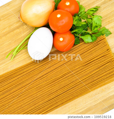 Raw healthy macaroni pasta stick and organic tomato, parsley, egg and onion, on bamboo cutting board Raw healthy macaroni pasta stick and organic tomato, parsley, egg and onion, on bamboo cutting board 109519218
