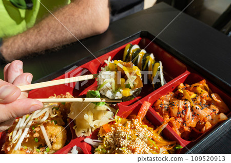 Japanese Lunch in Bento Box with Deep-Fried Squid Rings, Sushi Rolls, Salad, Rice, Pickled Ginger Japanese Lunch in Bento Box with Deep-Fried Squid Rings, Sushi Rolls, Salad, Rice, Pickled Ginger 109520913