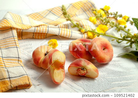Halves and three whole saturn peaches or flat peach on white wooden background.. 109521402
