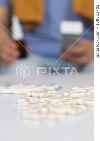 Pills on the table and a sick person with medicines in the hands. 109521702