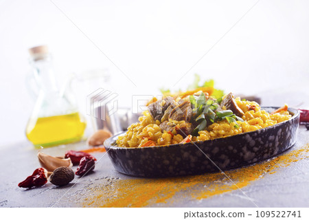 Pilaf, a dish of rice, chicken, carrots with spices and dried cranberries on a black plate 109522741