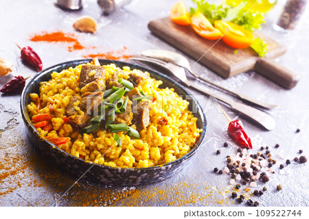 Pilaf, a dish of rice, chicken, carrots with spices and dried cranberries on a black plate 109522744