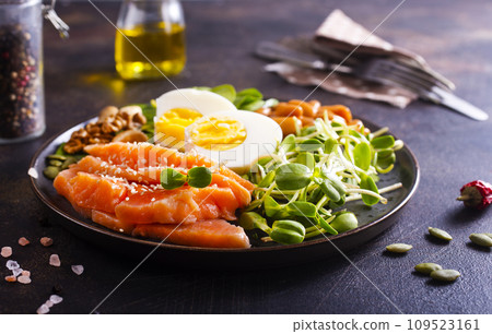 Keto diet breakfast. Salt salmon salad with greens, cucumbers, eggs and avocado. 109523161