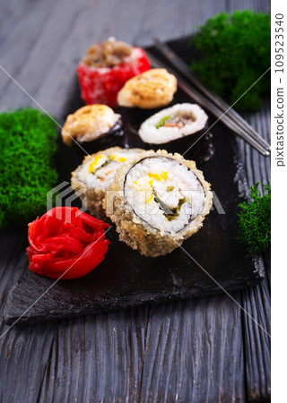 Sushi roll with salmon, smoked eel, avocado, cream cheese on black background. Sushi menu. Japanese food. 109523540