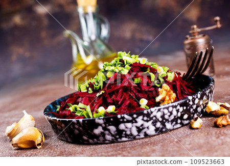 Beetroot salad with wallnuts and garlic in bowl on wooden table. Selective focus. 109523663