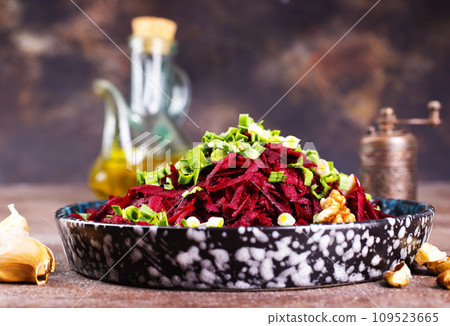 Beetroot salad with wallnuts and garlic in bowl on wooden table. Selective focus. Beetroot salad with wallnuts and garlic in bowl on wooden table. Selective focus. 109523665