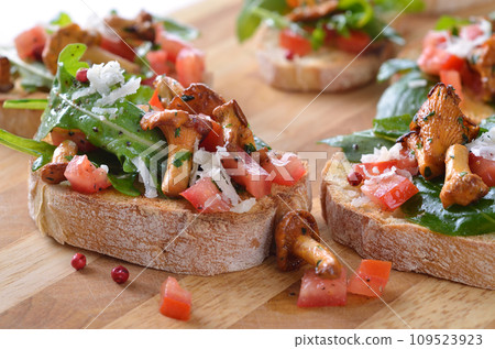 Delicious canapes with rucola-tomato-salad and fried chanterelles Delicious canapes with rucola-tomato-salad and fried chanterelles 109523923