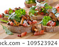 Delicious canapes with rucola-tomato-salad and fried chanterelles 109523924